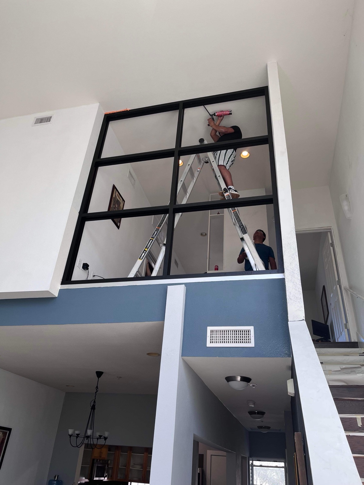 Two-story interior glass wall installation — two-man crew on ladders